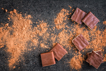 Milk chocolate bar chocolate chips and cocoa on black background