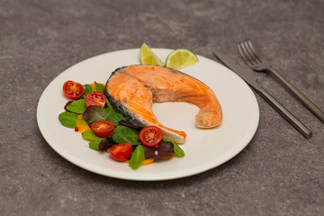 Salmon steak dinner with herbs and tomatoes.