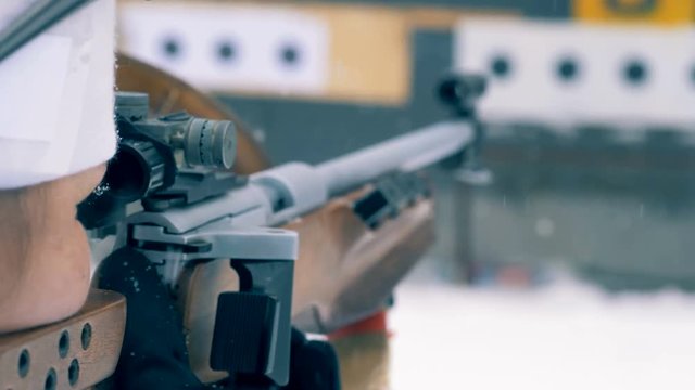 Female biathlete is preparing to shoot from a rifle