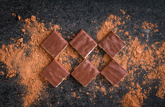 Milk chocolate bar chocolate chips and cocoa on black background