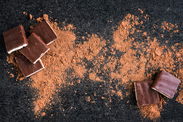 Milk chocolate bar chocolate chips and cocoa on black background