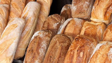 Variety of different breads assorted on shelf for sale on bakery shop