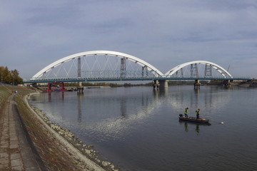 Fototapeta na wymiar New bridge over Danube in Novi Sad, two fishermenin the boat on the river