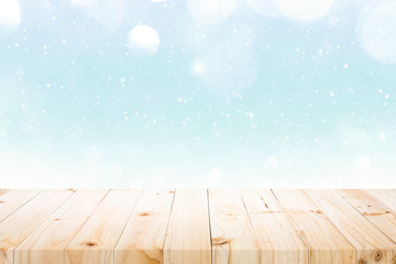 Wooden table on winter snow and white bokeh abstract.