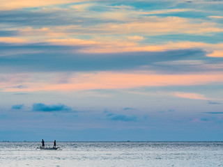 Indonesian fishermen fishing in the distance at sea