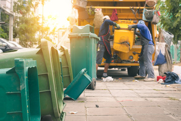 Garbage collector on the garbage truck.Sweeper or Worker are loading waste into the garbage truck...