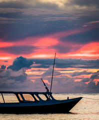 Pink and purple sky at sunset with boat silhouette