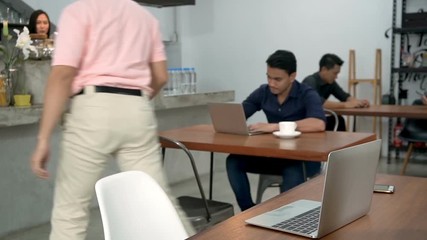 Businessman pick up his coffee at cashier to drink while working on laptop.