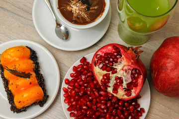 Homemade cake, pomegranate and coffee in a white cup on a wooden vintage table