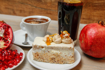 Homemade cake, pomegranate and coffee in a white cup on a wooden vintage table