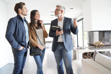   Couple with real-estate agent visiting modern house - obrazy, fototapety, plakaty
