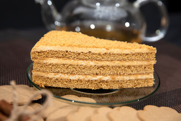 Honey cake lies on a saucer. Green tea in a cup and teapot.