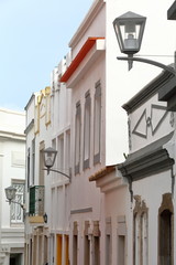 Fototapeta na wymiar Close-up on a row of colorful facades with lamps inside the old town of Tavira, Algarve, Portugal