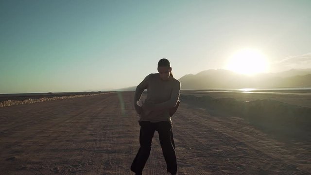 Attractive dancer girl dancing freestyle in the desert in sun rays slow motion