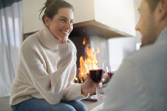  Couple relaxing by the fire enjoying glass of red wine