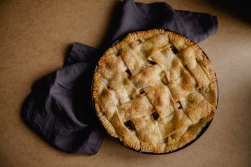 Apple pie with lattice decoration on beige background with a textile napkin