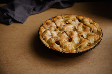 Apple pie with lattice decoration on beige background with a textile napkin