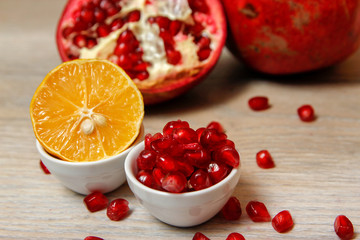Whole pomegranate, part of pomegranate and pomegranate seeds on wooden table