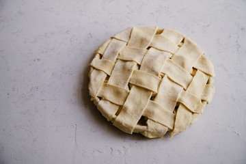 Uncooked apple pie with a wide lattice on top. Concrete background, preparation process.