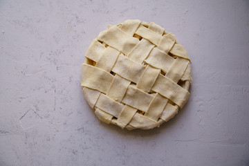 Uncooked apple pie with a wide lattice on top. Concrete background, preparation process.