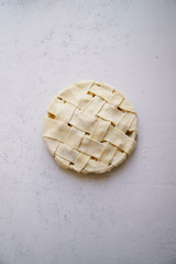Uncooked apple pie with a wide lattice on top. Concrete background, preparation process.
