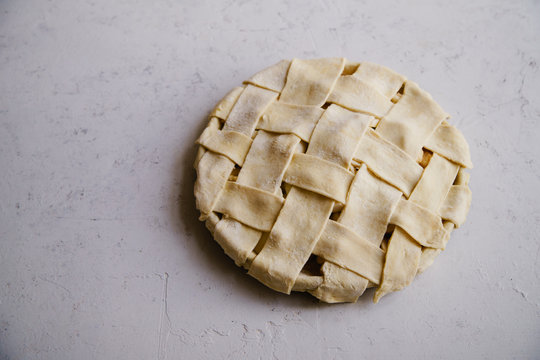 Uncooked apple pie with a wide lattice on top. Concrete background, preparation process. - Powered by Adobe