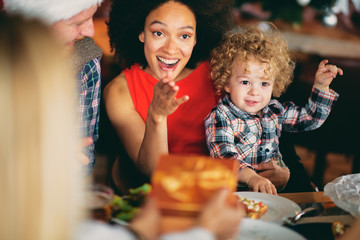 Mixed race woman holding toddler while sitting at table. Christmas eve concept