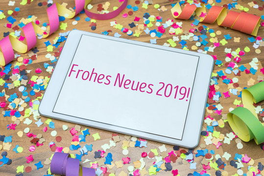 Frohes neues Jahr 2019 geschrieben auf Tablet inmitten von buntem Konfetti und Luftschlangen