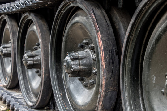 A closeup of tracks of an old tank. The part of tank with a large rubber-coated rollers.