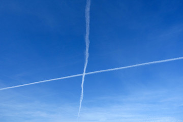 Kreuz Kondensstreifen vor blauem Himmel