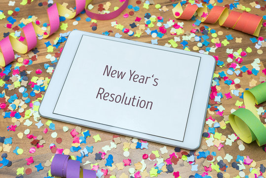 New year's resolution written on tablet with confetti and streamer in background