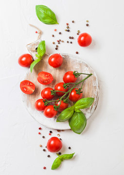 Organic Cherry Sugardrop Tomatoes on the Vine with basil and pepper on chopping board on stone kitchen background.