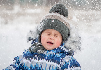 Little boy on snowy day playing snowballs