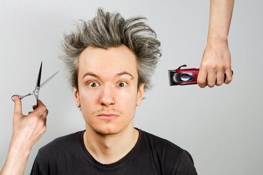 hand with clipper and hand with scissors cut overgrown unshaven guy with a beard on a white background