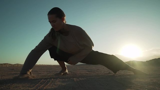 Beautiful flexible dancer girl dancing in the desert in sun glare slow motion