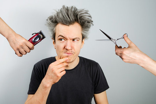 hand with clipper and hand with scissors cut overgrown unshaven guy with a beard on a white background