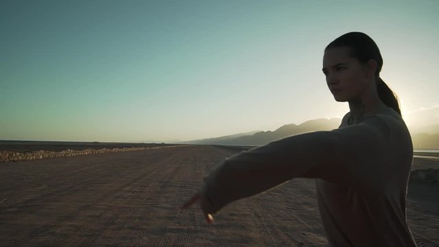 Adorable flexible dancer girl dancing in the desert in sun glare slow motion