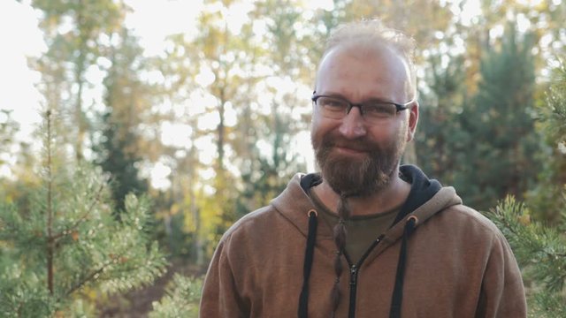 Portrait of a bald man with glasses and a beard, who rejoices against the autumn forest
