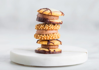 Luxury belgian chocolate and biscuit cookies selection on marble coasters and white kitchen table background.