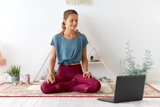 fitness, technology and healthy lifestyle concept - woman with laptop computer at yoga studio