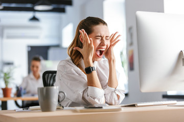 Obraz premium Happy young businesswoman sitting at her workplace