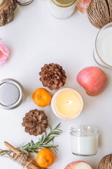 Candle, pine, apple, cinnamon on the white table.