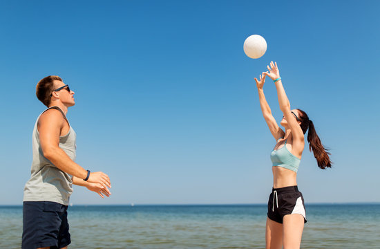 fitness, sport and lifestyle concept - happy couple with ball playing volleyball on summer beach