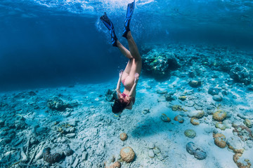 Woman free diver in bikini swim to deep in the tropical blue ocean