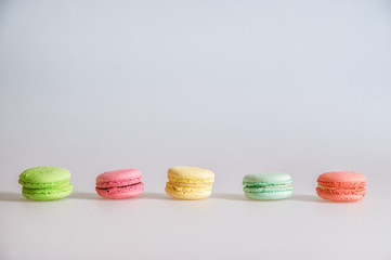 Close up. An assortment of bright colorful macaroons lined up in a row on a white background. Copy space.