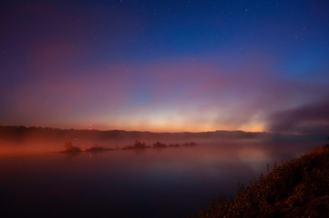 Mist over river in autumn. Darkening sky with stars after sunset.