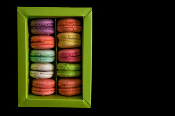 Flat lay. Close up. Sweet and colorful french macarons set in a light green box, isolated on a black background. Copy space.