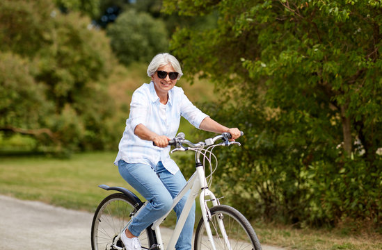 active old age, people and lifestyle concept - happy senior woman riding fixie bicycle at summer park