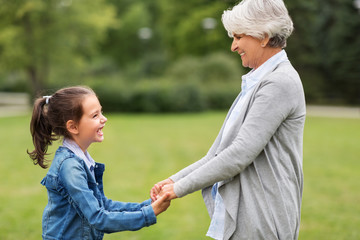 family, leisure and people concept - happy grandmother and granddaughter playing game or dancing at...