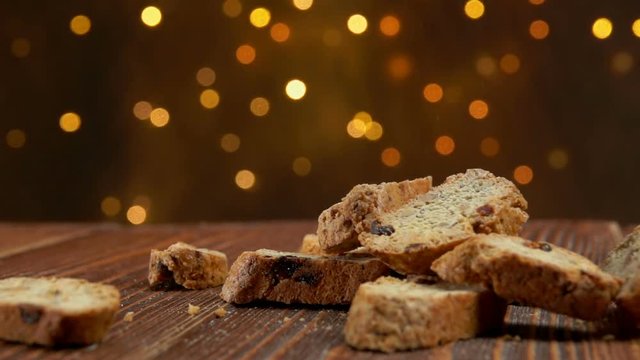 italian cantucci with almond and cranberries falls on a wooden surface against the background of Christmas light strings